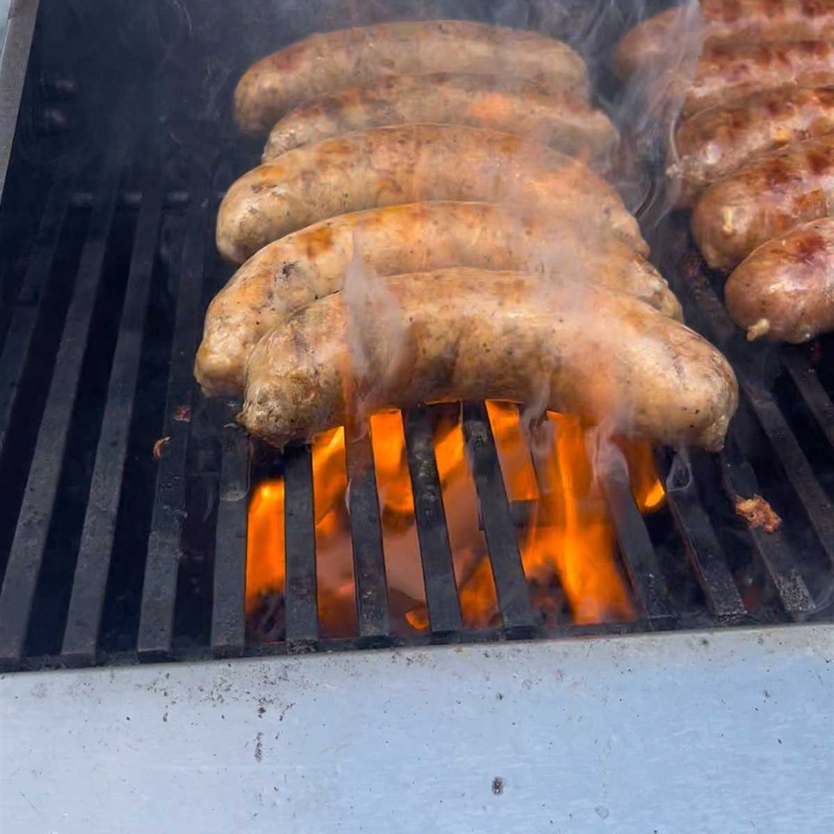 Chorizo's Factory chorizo searing over open flames, ready for a choripan with cilantro chimichurri